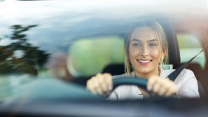 Aparece una mujer sonriente conduciendo un coche. Es la imagen de nuestro artículo de blog Placer al volante. ¿Por qué nos gusta conducir?