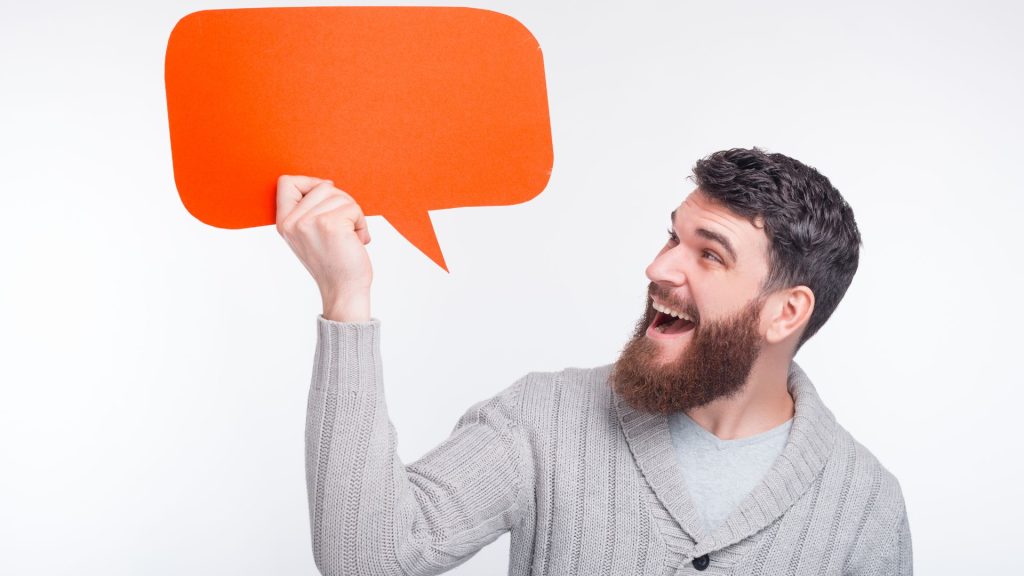 Hombre sonriendo mirando a un bocadillo naranja de texto vacío que sostiene con su mano