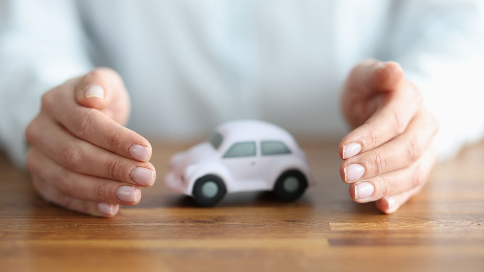 En la imagen aparecen unas manos como protegiendo un coche blanco pequeño. Es nuestra portada del artículo del blog miedo a conducir