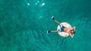 En la foto aparece un hombre subido a un flotador en un mar muy azul